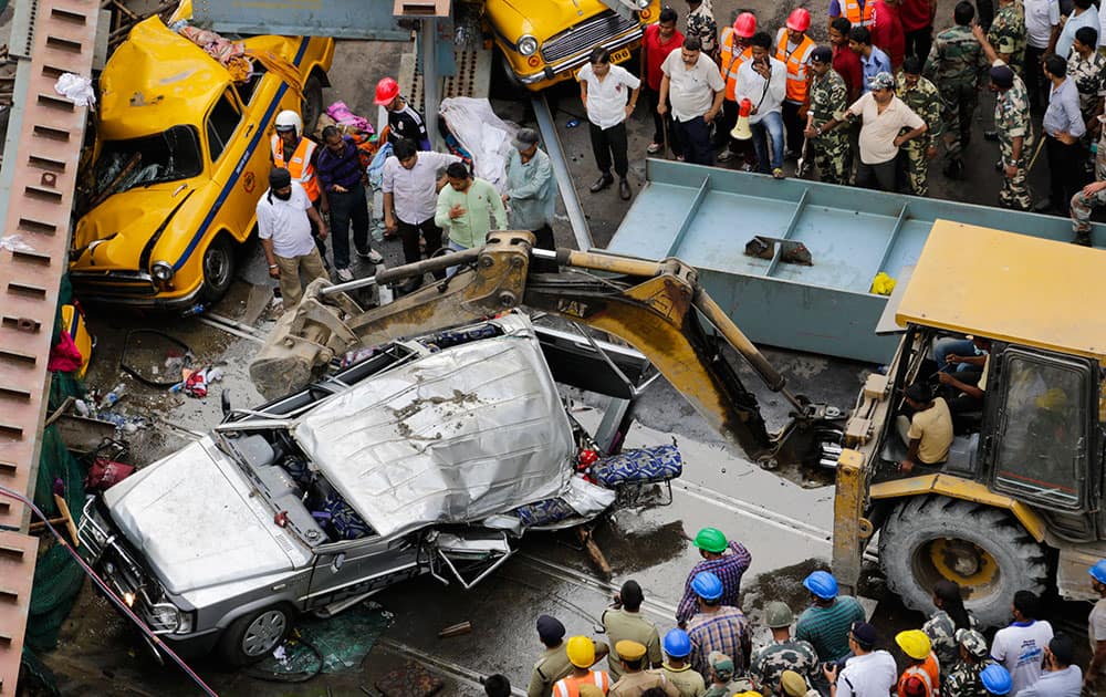 Rescue workers look at the mangled remains of a vehicle taken out from underneath a partially collapsed overpass in Kolkata.