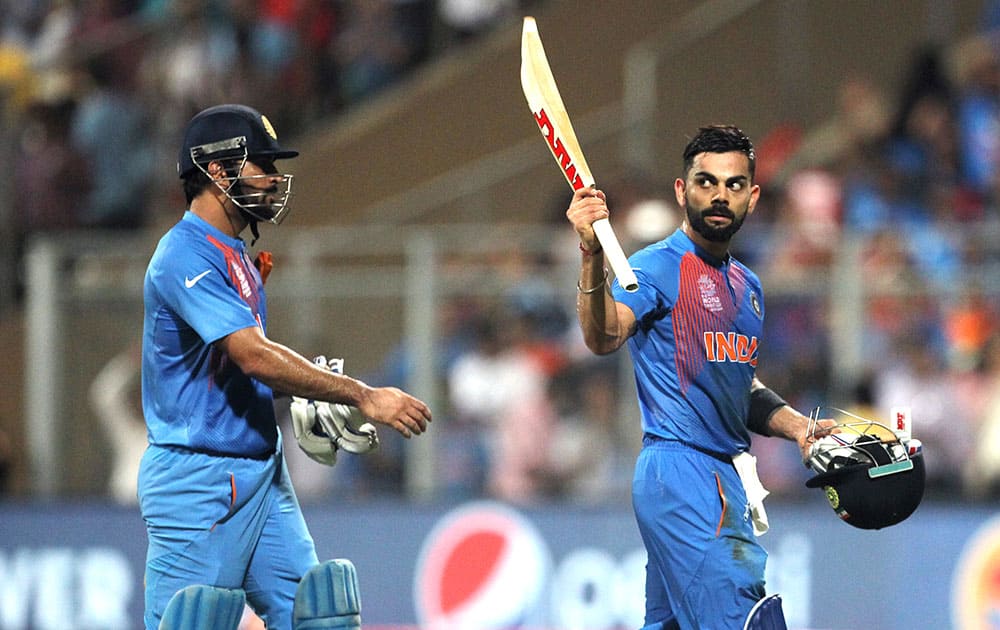 Virat Kohli waves his bat to the crowd as he leaves the field with teammate MS Dhoni during their ICC World Twenty20 2016 cricket semifinal match against the West Indies at Wankhede stadium in Mumbai.