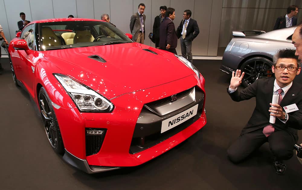 A visitor is briefed near a new 2017 Nissan GT-R model unveiled by the Nissan Motor Co. at its global headquarters gallery in Yokohama, near Tokyo.