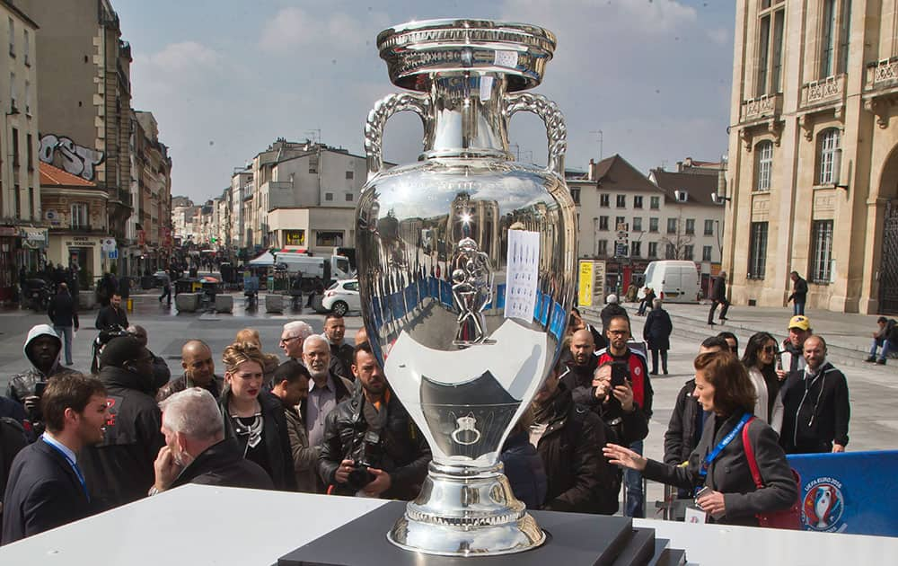 People gather next to the European soccer championships trophy who is put on display in Saint-Denis north of Paris