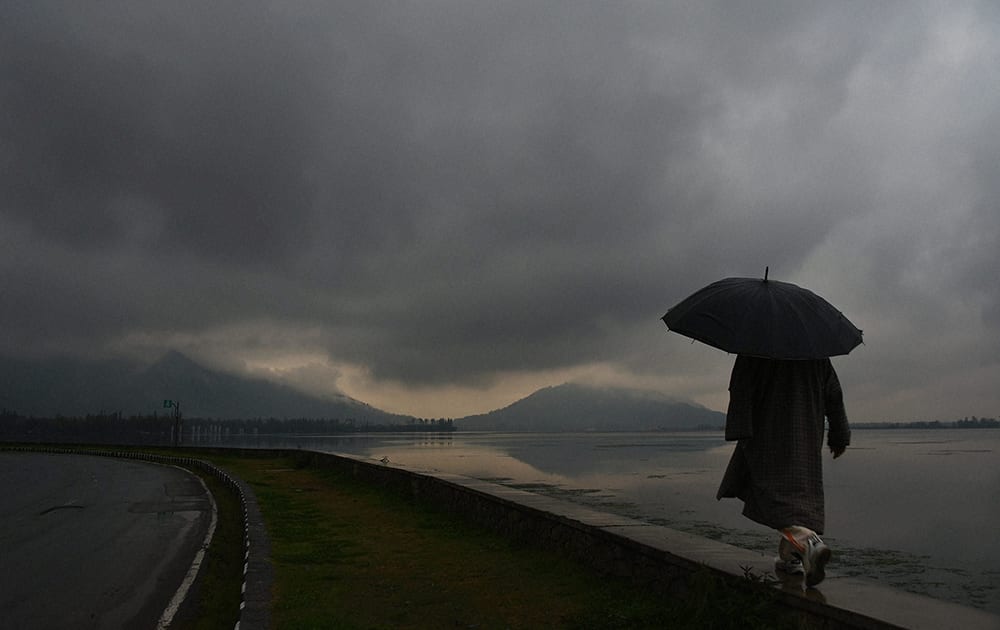 A man walks umbrella on the banks on Dal Lake as it rains in Srinagar.