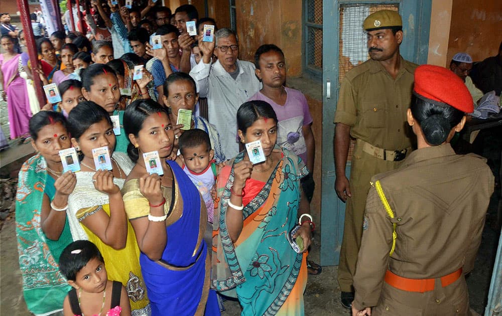 Women voters stand in queue at a polling booth to caste their vote during the first phase of the Assam assembly polls in Silchar.