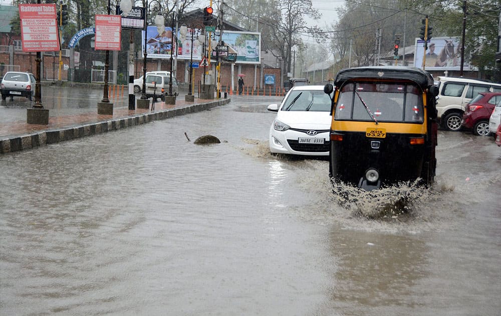 Vehicles move through a waterlogged road due to heavy rains, at Regal Chowk in Srinagar.