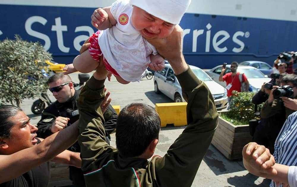 A migrant man holds a baby over his shoulders during tension with port police officers at the Athens port of Piraeus.