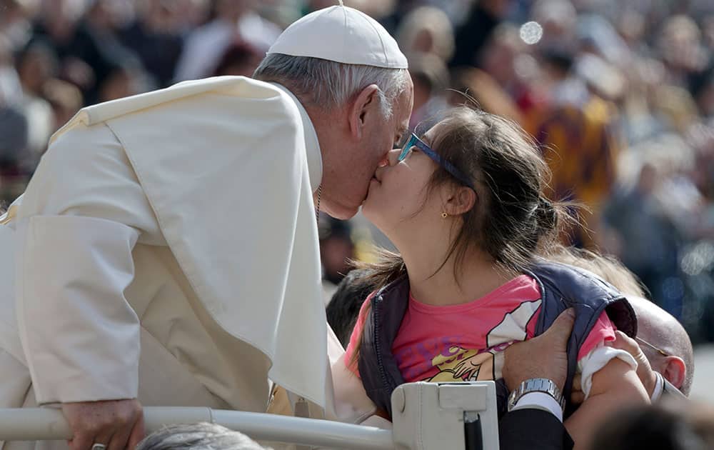 Pope Francis gets a kiss from a girl during his weekly general audience, in St. Peter's Square at the Vatican.