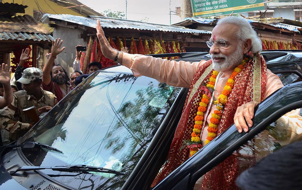 Prime Minister Narendra Modi waves to his supporters as he leaves after offering prayers the Kamakhya temple in Guwahati.