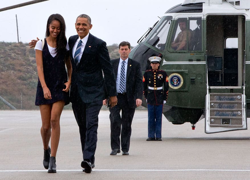 President Barack Obama walks with daughter Malia Obama through a light rain to from Marine One to board Air Force One prior to leaving Los Angeles