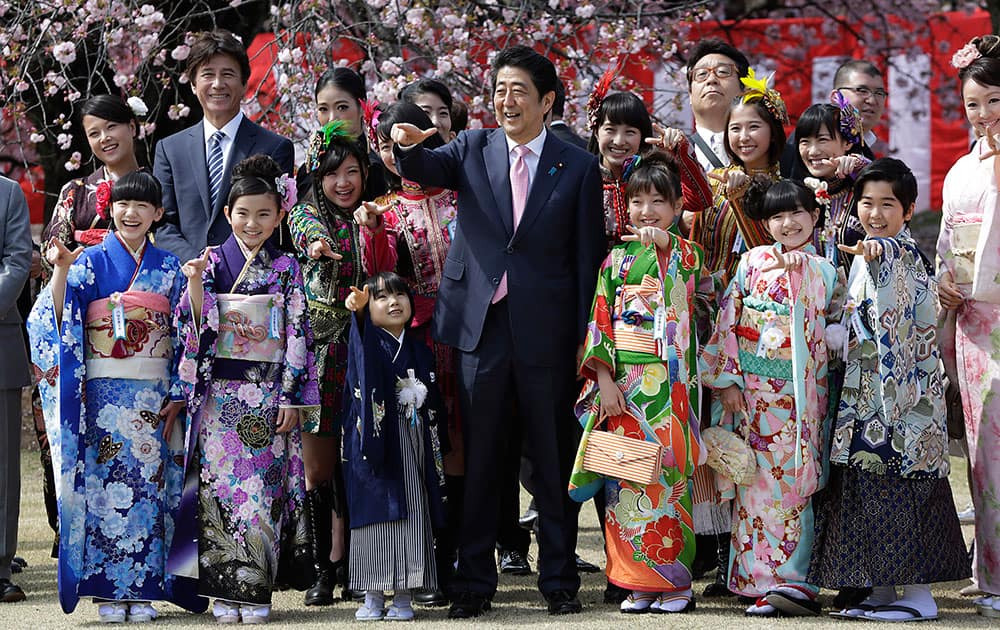 Japanese Prime Minister Shinzo Abe, center, poses for a group photo with members of Japanese pop group Momoriro Clover Z and Japanese child actors wearing Japanese kimono during a cherry blossom viewing party hosted by Abe at Shinjuku Gyoen National Garden in Tokyo.