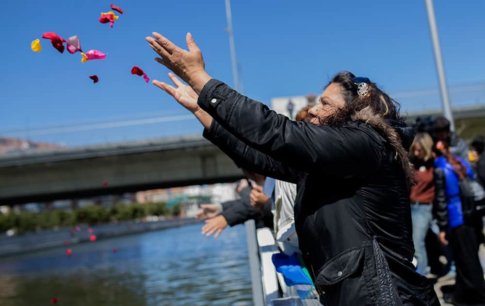 A woman, and others members of the Spain's gypsy community, throw flower petals into the Manzanares river during an event marking the International Roma Day in Madrid.