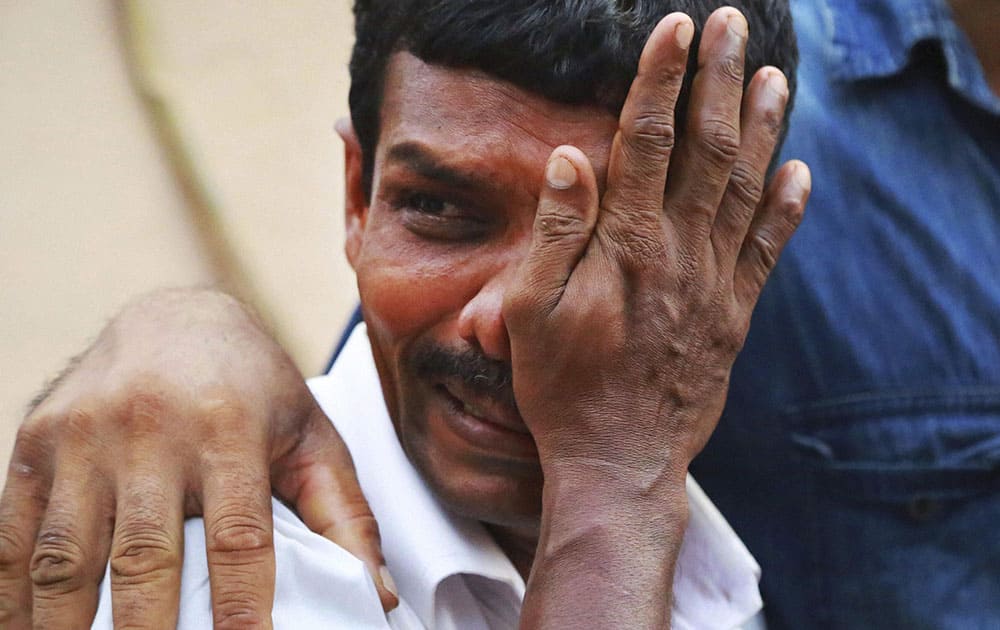 An unidentified man weeps as bodies of victims lie outside a morgue at the Kollam district hospital after a massive fire broke out during a fireworks display at the Puttingal temple complex in Paravoor village, Kollam district, southern Kerala.