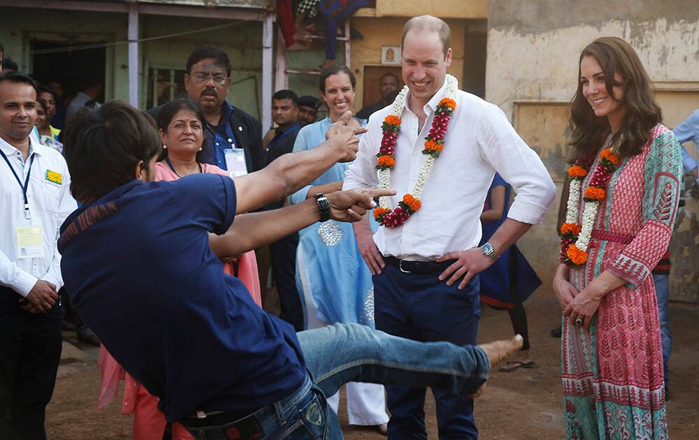 A boy performs dance for Britain's Prince William, second right and his wife Kate, the Duchess of Cambridge, right, during their visit to a slum in Mumbai.