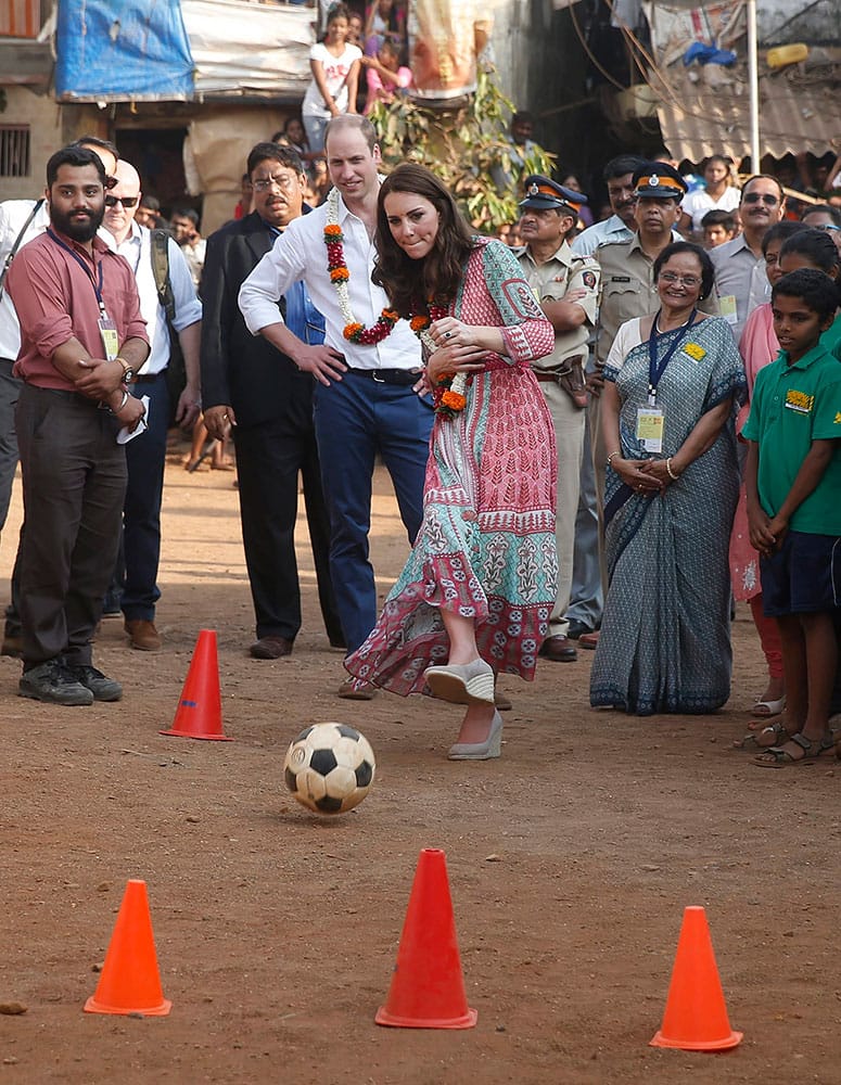 Britain's Prince William, watches as his wife Kate, the Duchess of Cambridge, plays soccer during their visit to a slum in Mumbai.