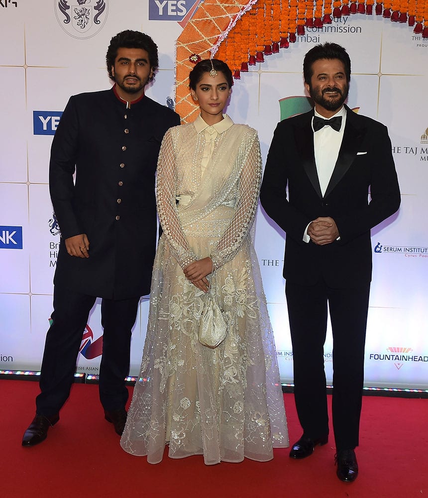 Bollywood actress Sonam Kapoor, center, actors Anil Kapoor, right and Arjun Kapoor pose for photographers after arriving for a charity ball at the Taj Mahal Palace hotel attended by the Duke of Cambridge, Prince William, and his wife, Kate, the Duchess of Cambridge, in Mumbai.