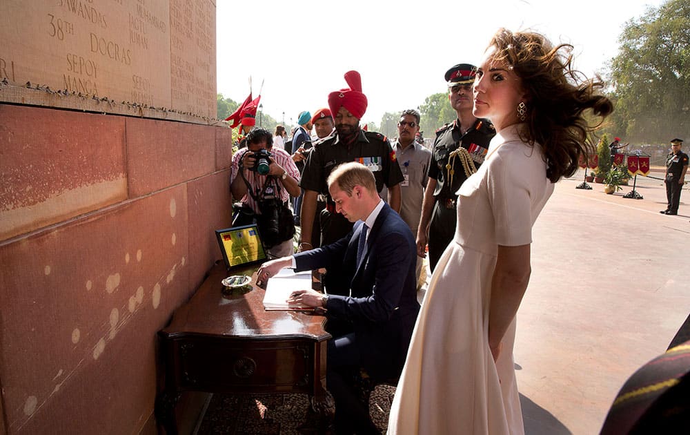 Britain's Prince William, signs visitor's book as his wife Kate, the Duchess of Cambridge looks on after paying their tributes at the India Gate war memorial, in the memory of the soldiers from Indian regiments who served in World War I, in New Delhi.