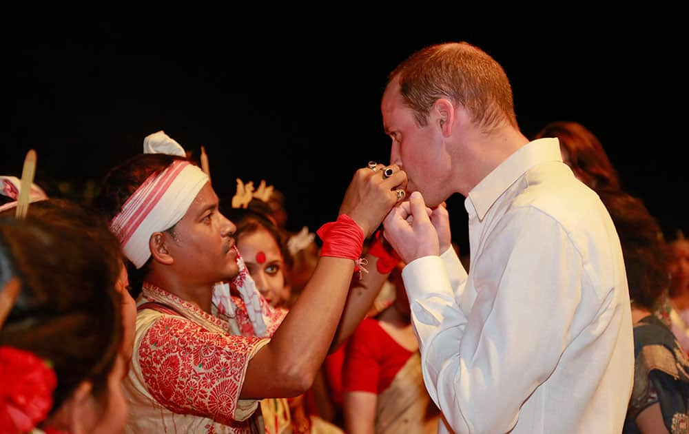 An Assamese traditional Bihu dancer explains to Britain's Prince William, right, how to play a traditional instrument made of bamboo in Diphlu River Lodge in the Kaziranga National Park, east of Gauhati, northeastern Assam state.