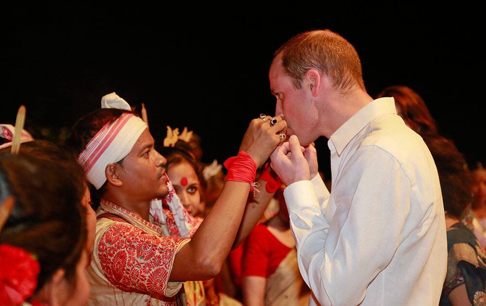 An Assamese traditional Bihu dancer explains to Britain's Prince William how to play a traditional instrument made of bamboo in Diphlu River Lodge in the Kaziranga National Park, Assam.