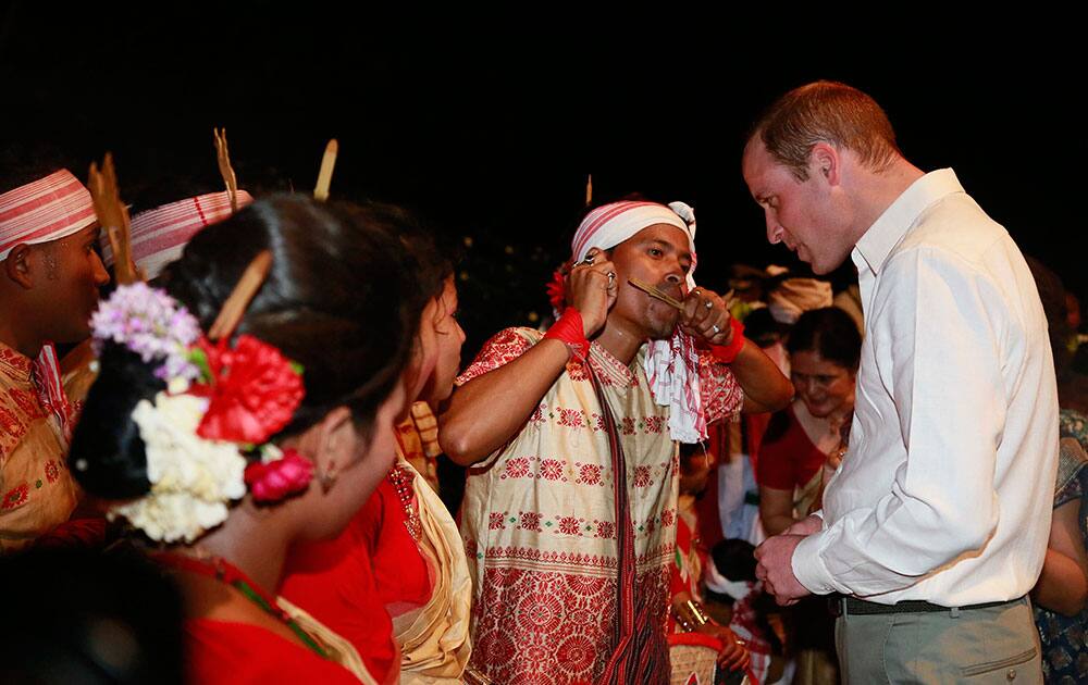 An Assamese traditional Bihu dancer explains to Britain's Prince William how to play a traditional instrument made of bamboo in Diphlu River Lodge in the Kaziranga National Park, Assam.