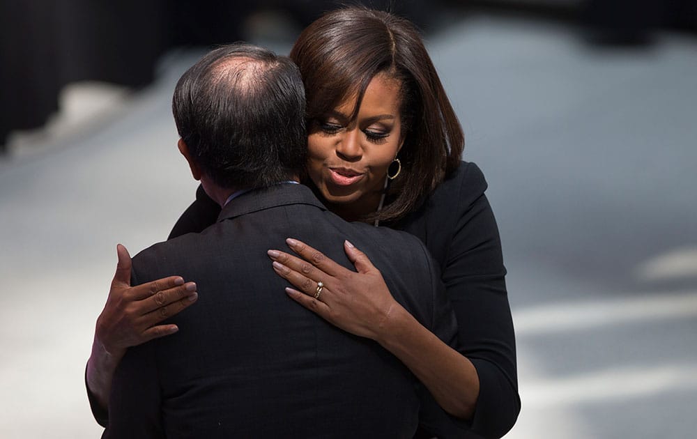 World Bank President Jim Yong Kim hugs first lady Michelle Obama as she arrives to speak during a 