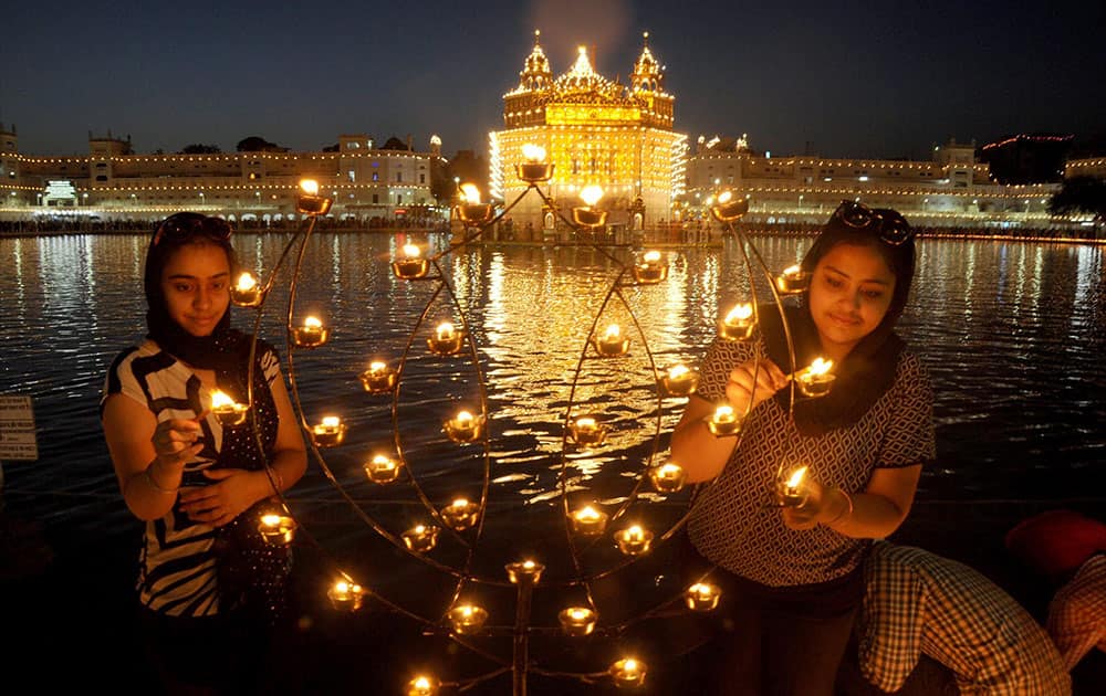 Devotees lights up candles at the illuminated Golden Temple on the occasion of “Baisakhi” festival at Amritsar.