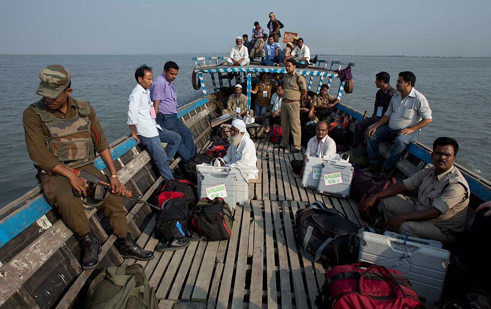 Polling officials and security personnel with electronic voting machines travel on a boat to cross the river Brahmaputra to reach a polling station near Bhatkhowa Chapori west of Guwahati, Assam.