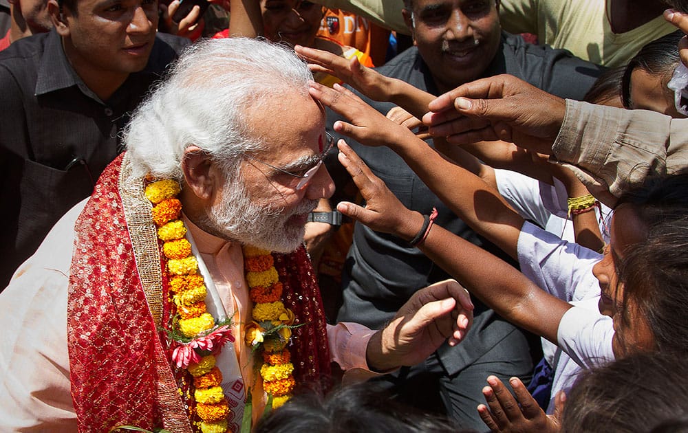People put tilak or red vermilion paste on to the forehead of prime minister Narendra Modi as he comes out of the Kamakhya temple after praying on the first day of Navratri festival in Gauhati. Modi is on a campaigning tour for the second and final phase of the state Assembly elections.