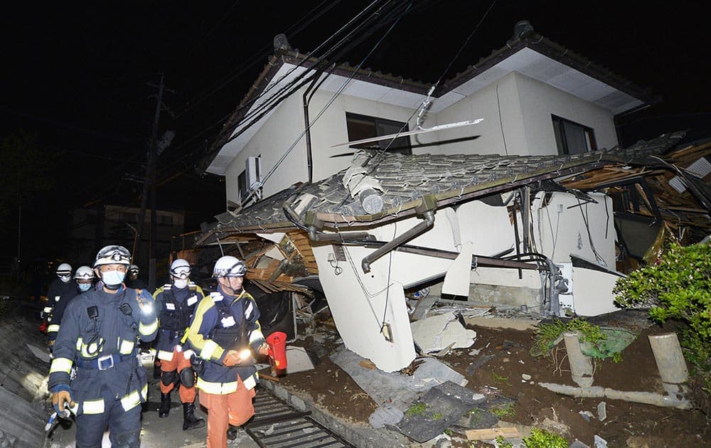 Firefighters check the damage of the collapsed house in Mashiki, near Kumamoto city, southern Japan, after the earthquake.