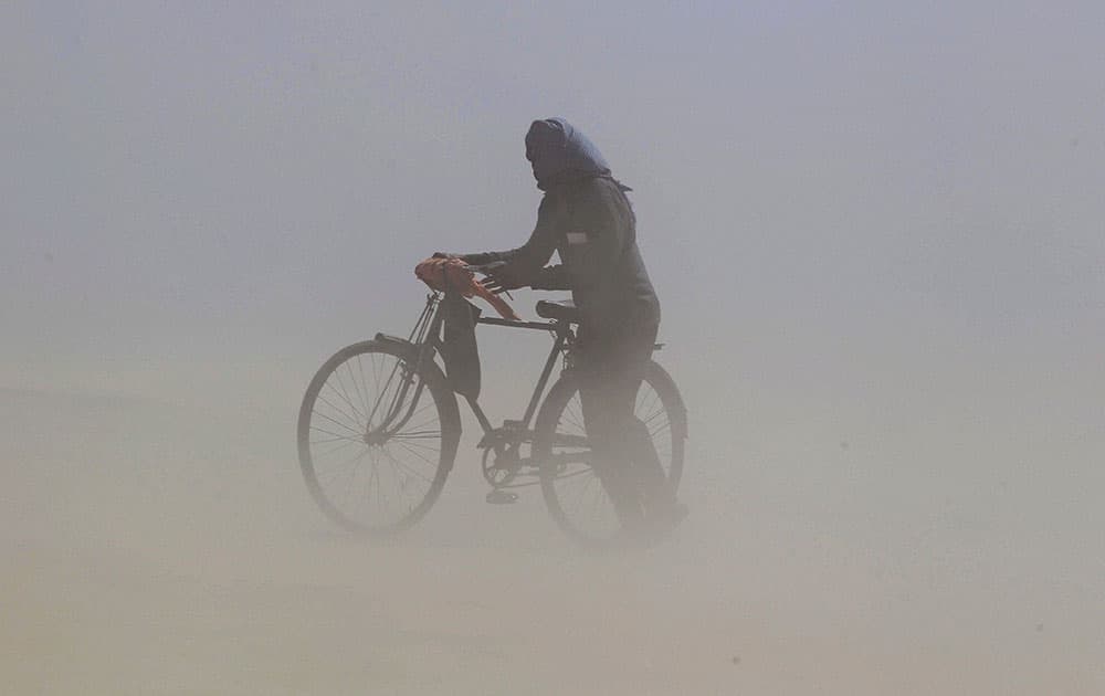 A cyclist cover himselves as he walk on the river bank of Ganga during a dust storm in Allahabad.
