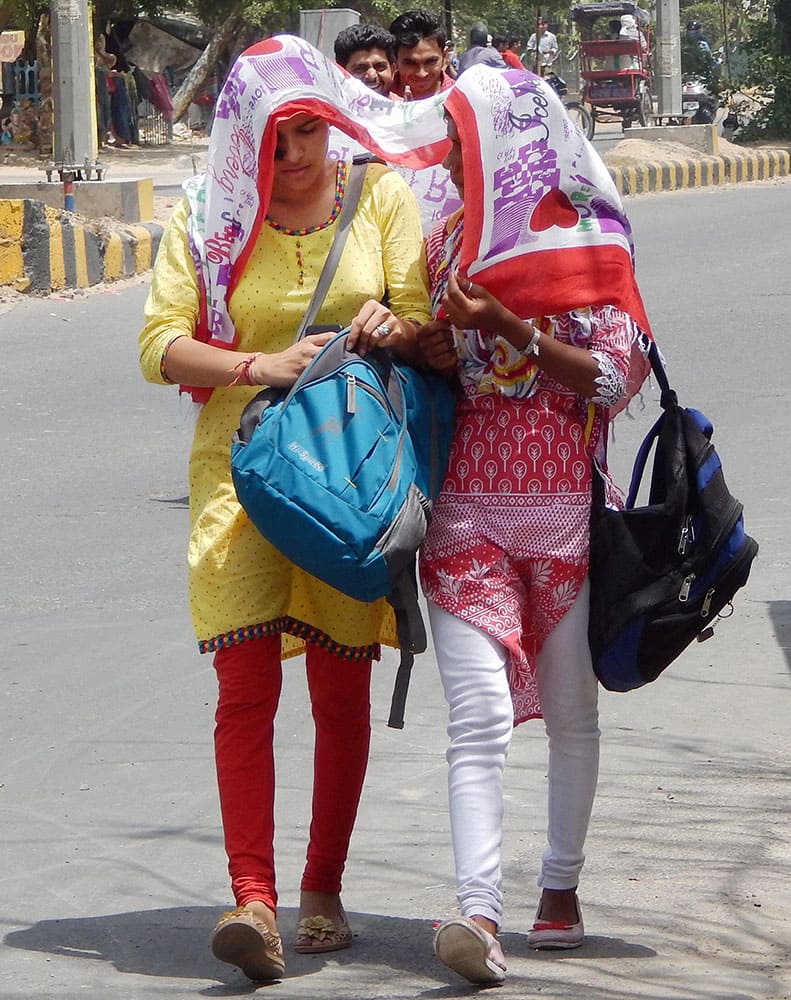 Girls cover themselves during a hot summer day in Gurgaon.