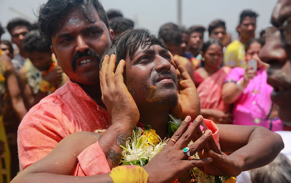 An Indian Tamil Hindu devotee offers prayers before being pierced with a metal spear at a religious procession during Muthu Mariamman Puja festival in Mumbai.