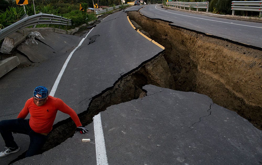 A man jokes around after taking some pictures of a section of highway that collapsed due to a 7.8-magnitude earthquake, in Chacras, Ecuador.