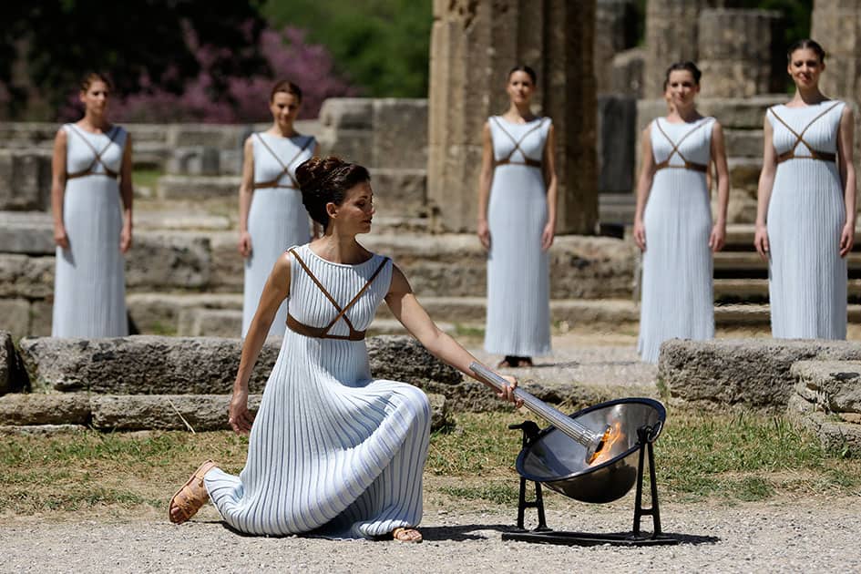 Actress Katerina Lehou, right, as high priestess, lights the Olympic Flame, during the final dress rehearsal of the lighting of the Olympic flame at Ancient Olympia, in western Greece.
