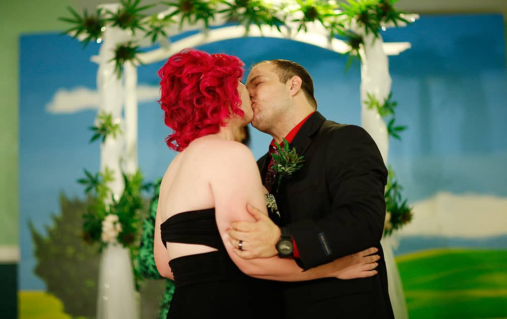 Natalie Rice, left, kisses her new husband Lee Rice beneath a canopy of faux marijuana plants during a ceremony at the Cannabis Chapel in Las Vegas.