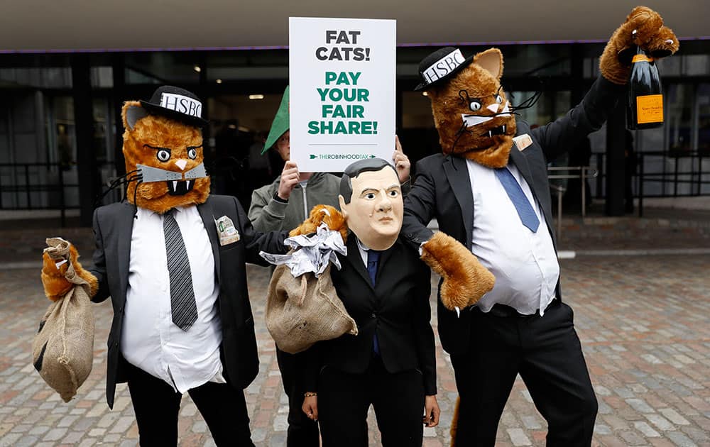 Robin Hood Tax campaigners pose for photographers dressed as fat cats and Britain's Chancellor of the Exchequer George Osborne outside the HSBC annual general meeting at the Queen Elizabeth II conference centre in London.