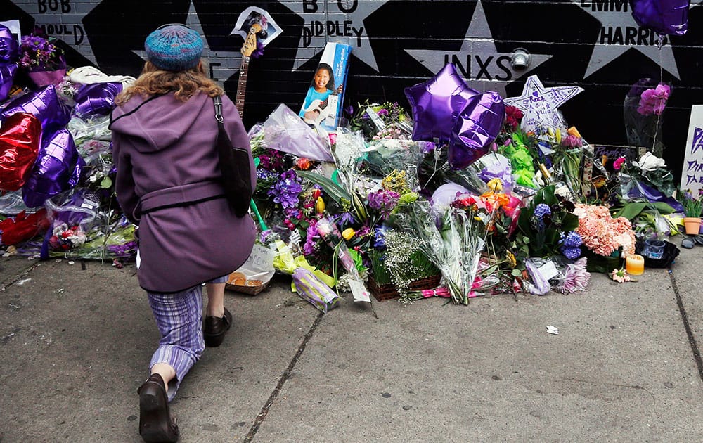 A woman kneels by the memorial at First Avenue, in Minneapolis where Prince often performed.