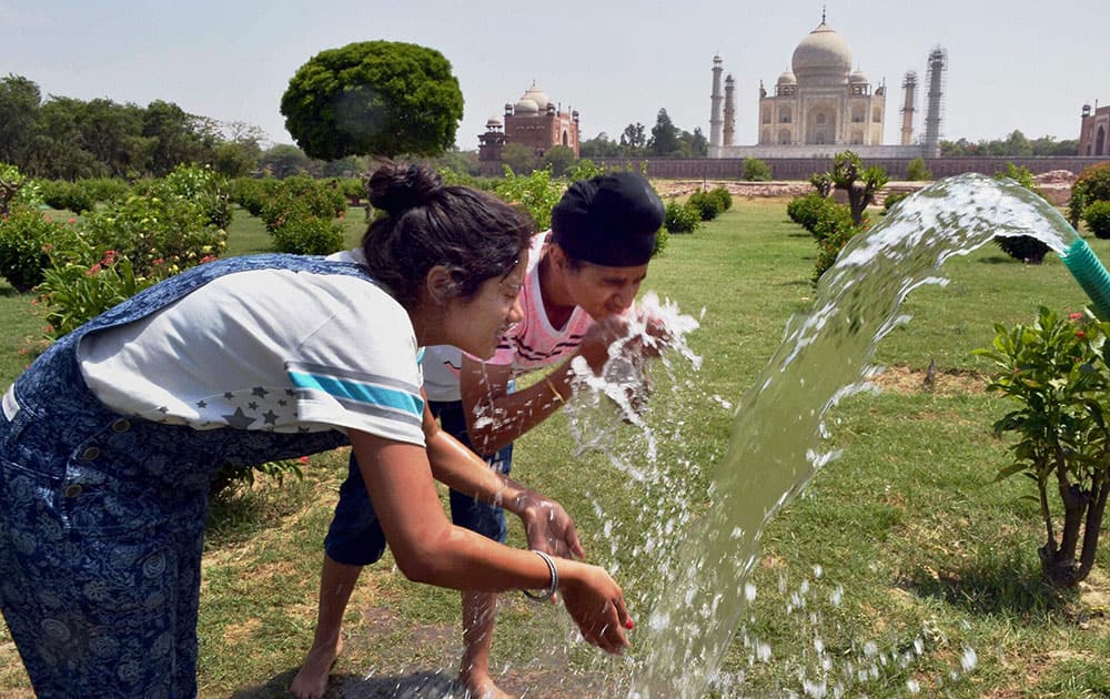 Tourists splash water on their faces to get relief from heat at Mehtab Bagh behind Taj Mahal during a hot summer day in Agra.