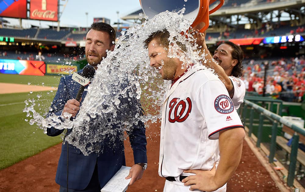 Washington Nationals' Chris Heisey, center, and MASN on-field reporter Dan Kolko, left, are doused with water by Anthony Rendon after an interleague baseball game against the Minnesota Twins in Washington. 