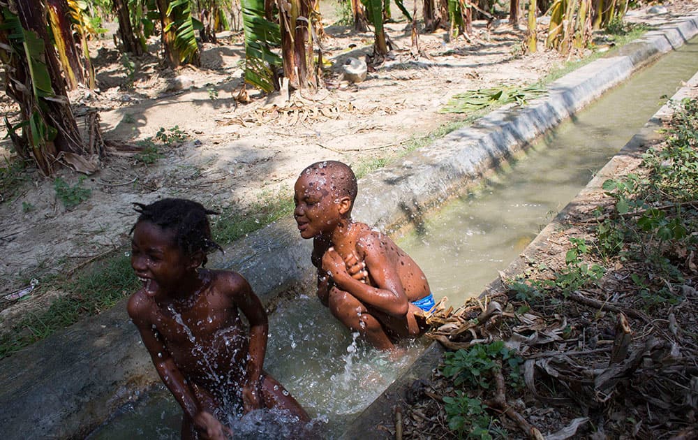 Adamson Castor, right, the son of slain deaf woman Jesula Gelin, bathing with a friend in an irrigation channel on a banana farm near Leveque, a community where a group of deaf people relocated after the 2010 earthquake in Cabaret, Haiti.