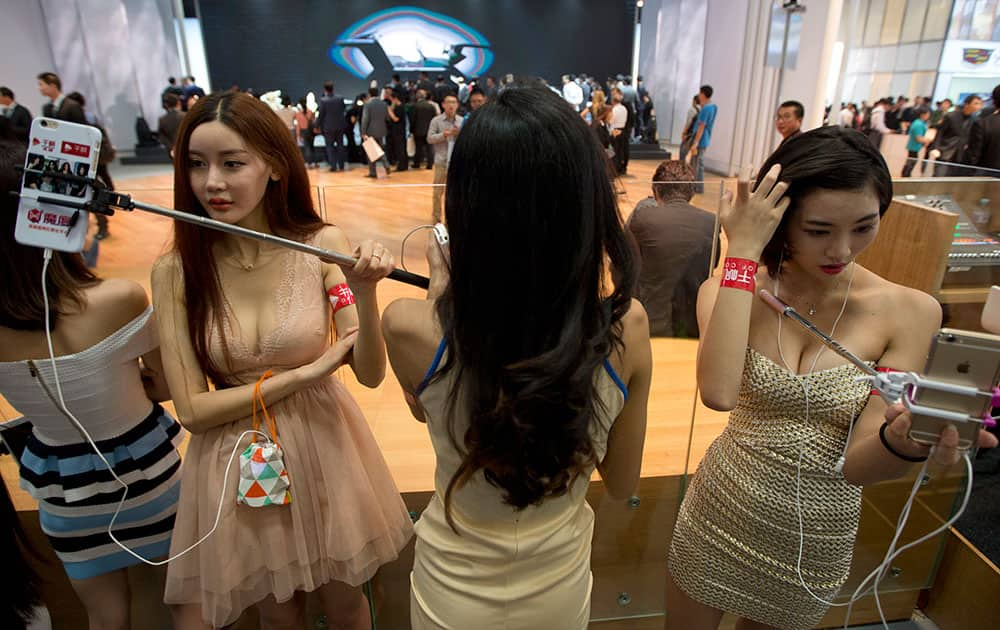 Former car models take on new roles as presenters of live online shows using their mobile phones and selfie sticks at the Auto China 2016 in Beijing, China.