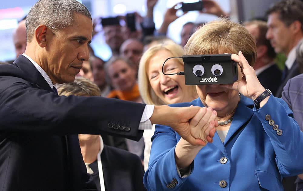 U.S. President Barack Obama, left, holds the hand of German Chancellor Angela Merkel as they test VR goggles when touring the Hannover Messe, the worlds largest industrial technology trade fair, in Hannover, northern Germany.