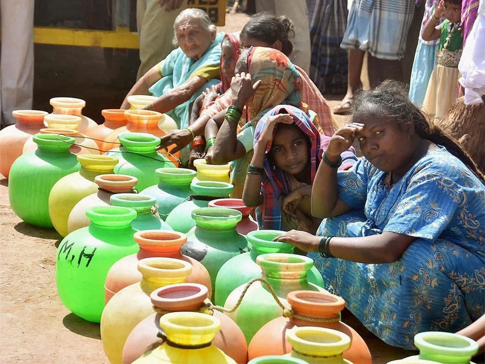 People wait with their pots to collect water at drought-hit Bhandivad village in Hubli.