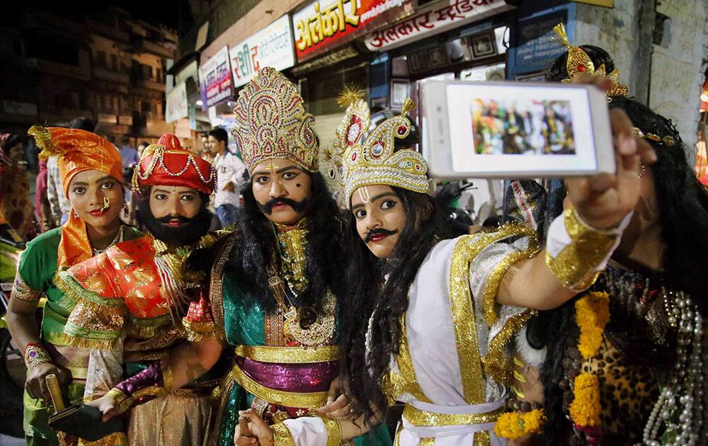 Women, wearing fancy costumes, take selfie during Dhinga Gavar festival in Jodhpur.