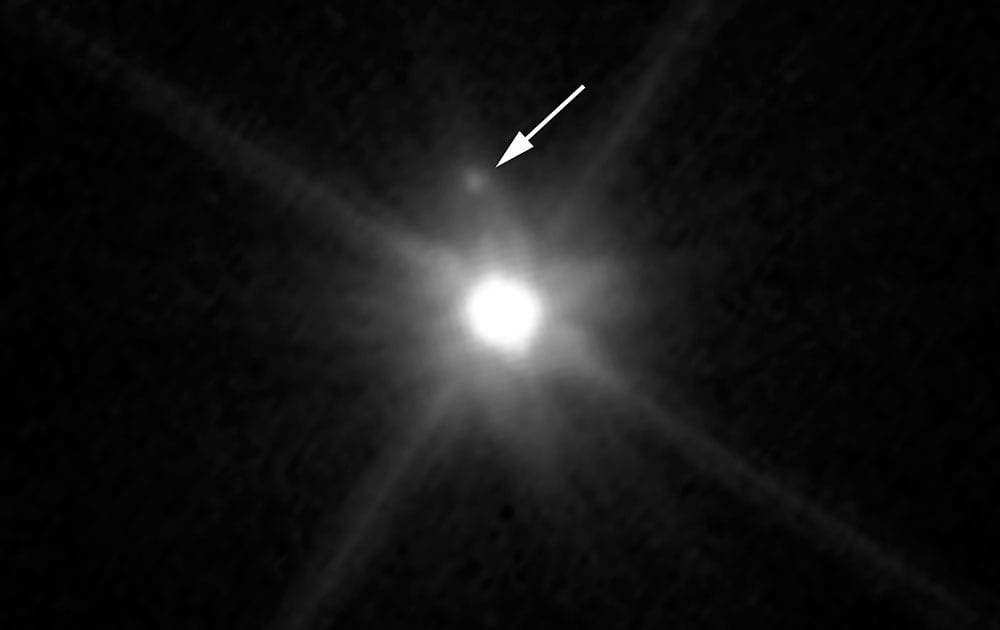 An undated photo provided by NASA and made by NASA’s Hubble Space Telescope shows a small, dark moon orbiting Makemake, the second brightest icy dwarf planet, after Pluto, in the Kuiper Belt. 