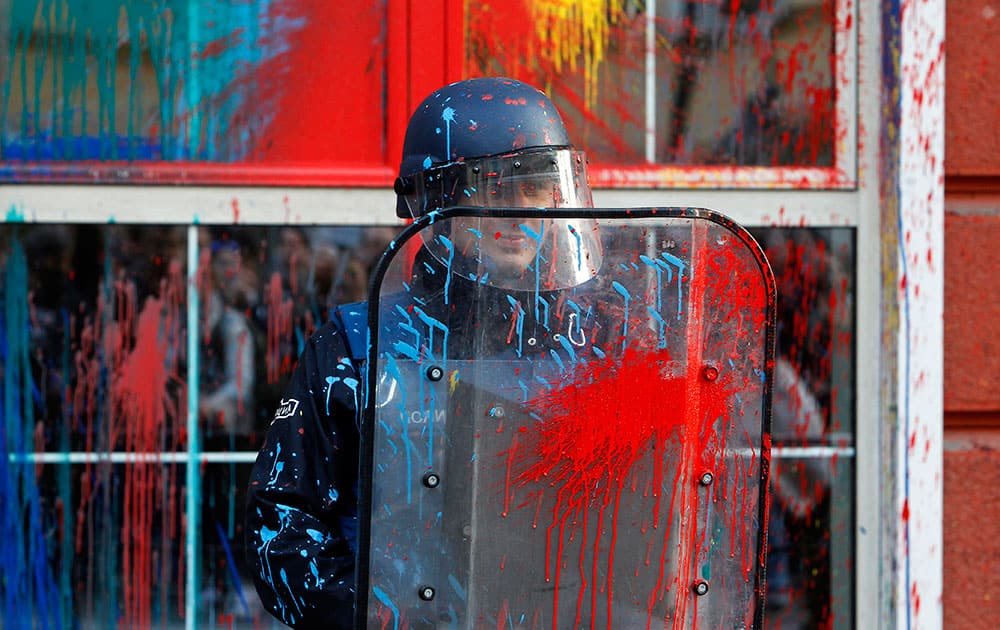 A police officer holds his shield as protestors pelt the facade of the Ministry of Justice with colored paint, during a protest in downtown Skopje, Macedonia.