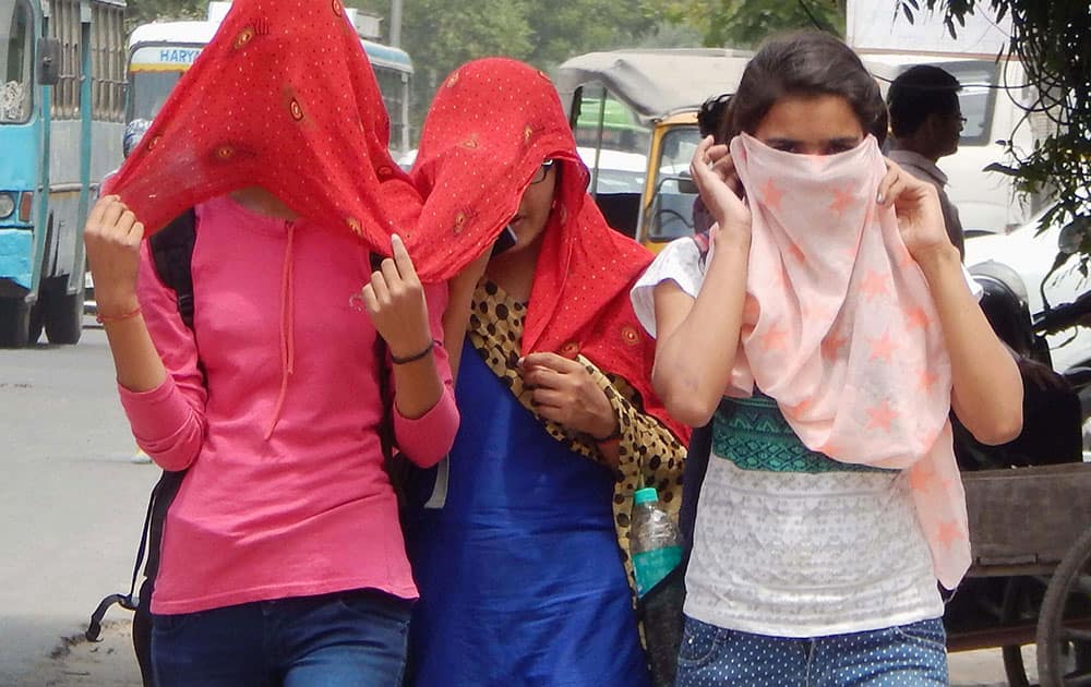 Girls cover themselves during a hot summer day in Gurgaon.
