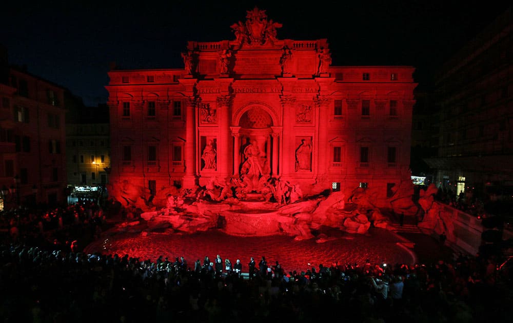 People gather to see the Trevi fountain illuminated red in memory of Christian Martyrs, in Rome.