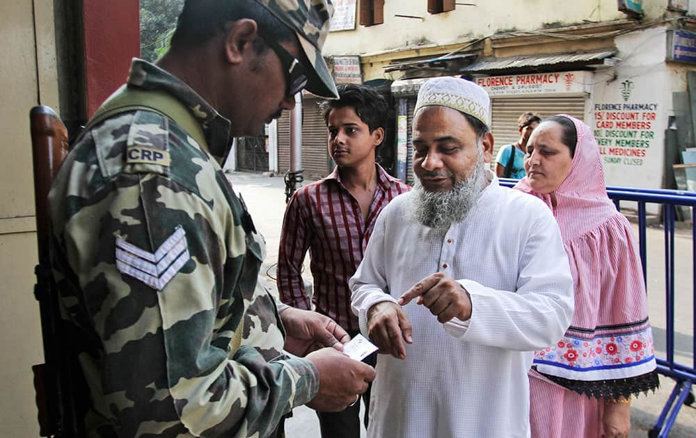 An Indian paramilitary soldier checks the identity of voters outside a polling booth during the third phase of voting in the West Bengal state Assembly elections, in Kolkata.