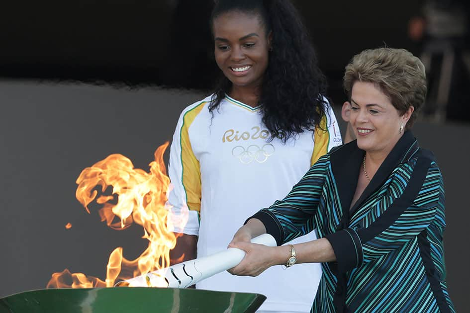 Brazil's President Dilma Rousseff lights the Olympic flame as Brazilian volleyball player Fabiana Claudino looks on during the lighting ceremony at Planalto presidential palace in Brasilia, Brazil.