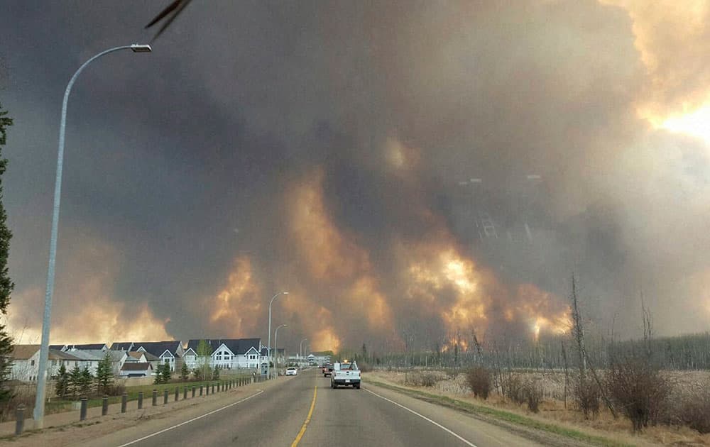 This photo taken through a car windshield shows smoke rising from a wildfire rages outside of Fort McMurray.