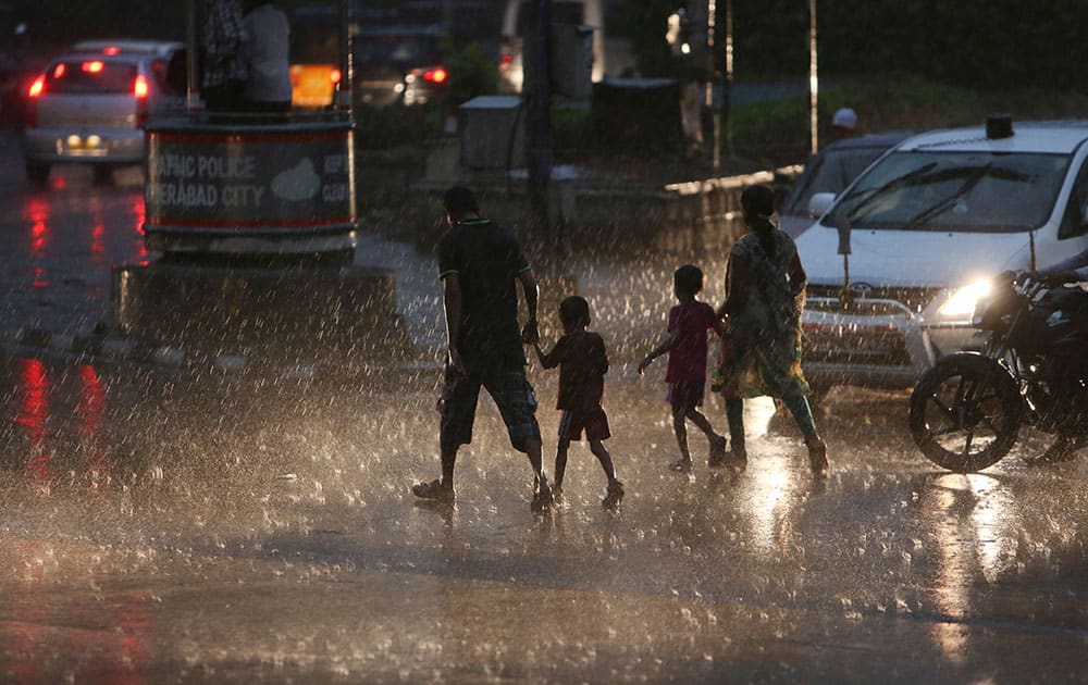 An Indian family crosses a road during a sudden rain in Hyderabad.