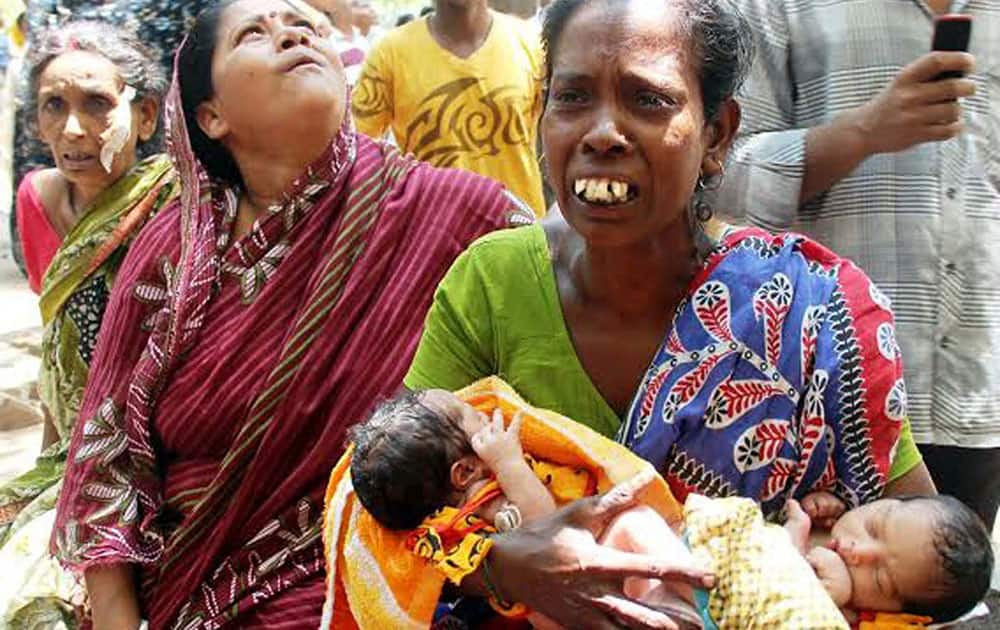 A women moves two new born babies out of a hospital after a fire at Burdwan Medical College and Hospital in West Bengal.